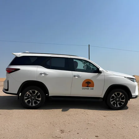 The Quiver Car Rental Toyota Fortuner on open desert gravel under a clear sky
